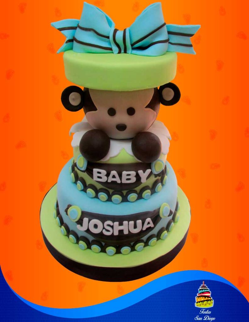 Torta de baby shower con figura de mono y un moño en colores café, azul y verde.